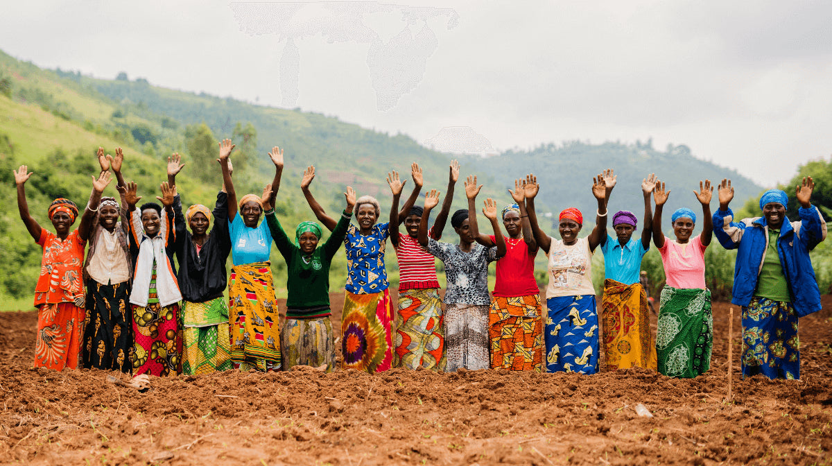 a group of women in a field raise their arms, looking at the camera