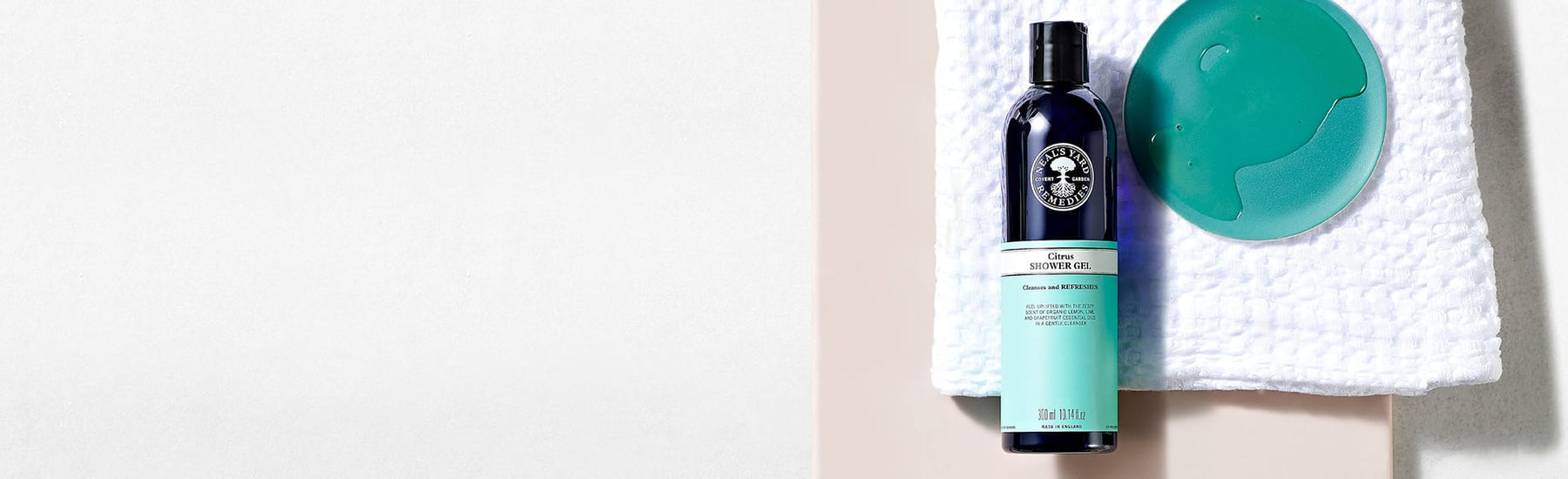 Picture of a bottle of Citrus Shower Gel on a white towel by Neal's Yard Remedies