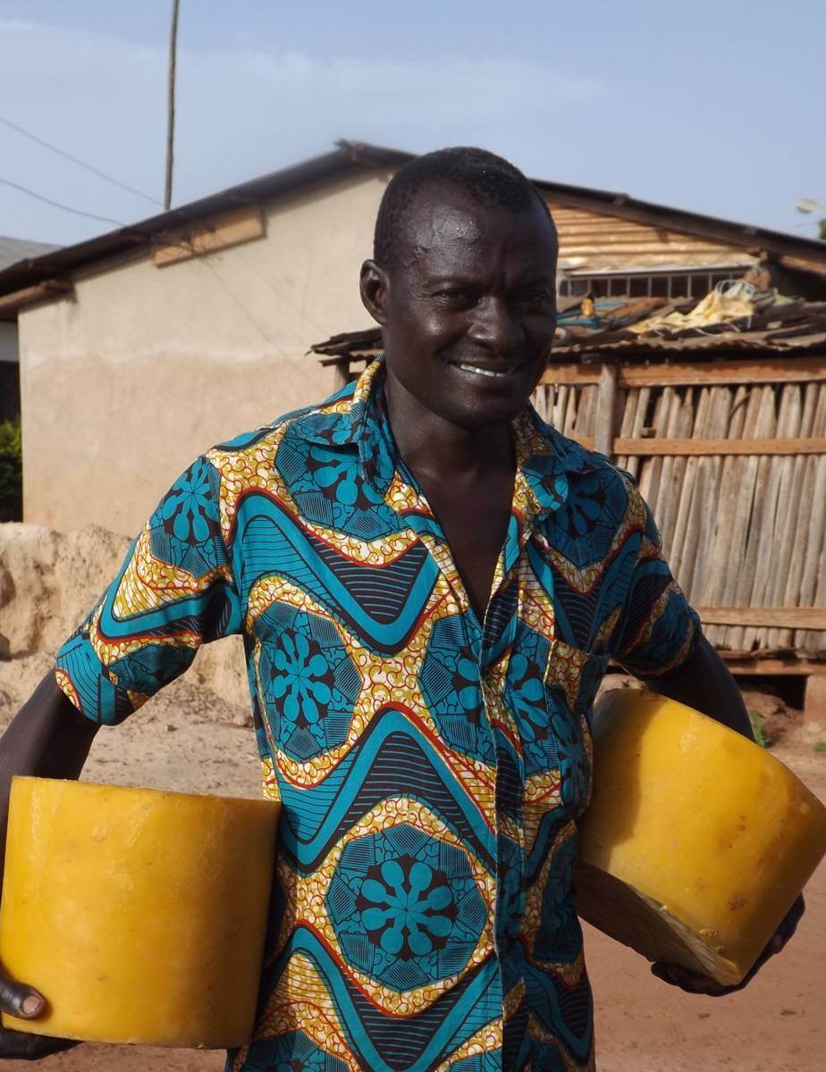Picture of a man carrying beeswax in both arms in Ghana