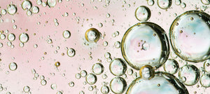 Close-up of oil bubbles on a pink water surface