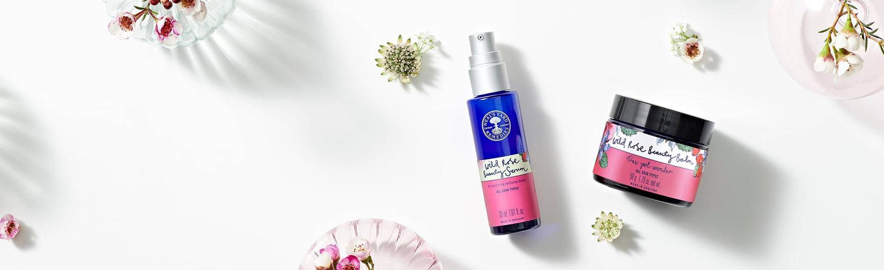 Picture of the award winning Wild Rose Beauty Balm and Beauty Serum with botanical background by Neal's Yard Remedies